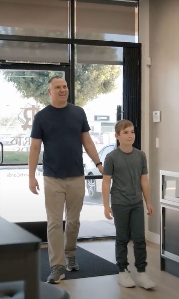 Man and young boy standing in a room with large windows